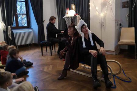 Foto zeigt drei Künstler des Vereins, die vor einem Kinder-Publikum performen